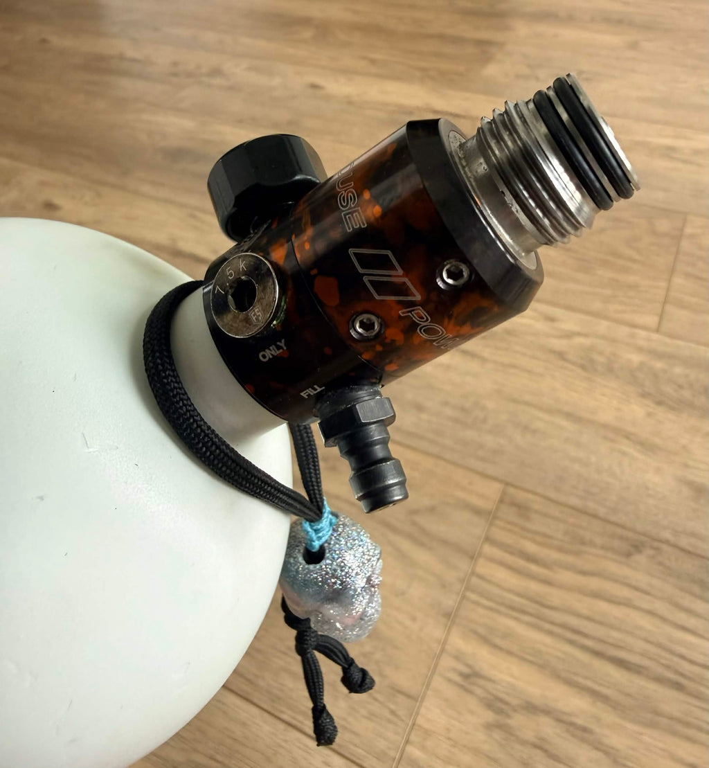 Handmade [REDACTED] frag tag hanging from white paintball air tank on wood floor background